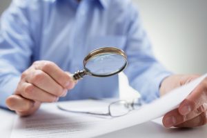 Businessman reading documents with magnifying glass concept for analyzing a finance agreement or legal contract